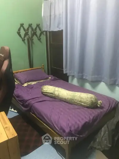 Cozy bedroom with purple bedding and gaming chair, ideal for relaxation and work-from-home setup.