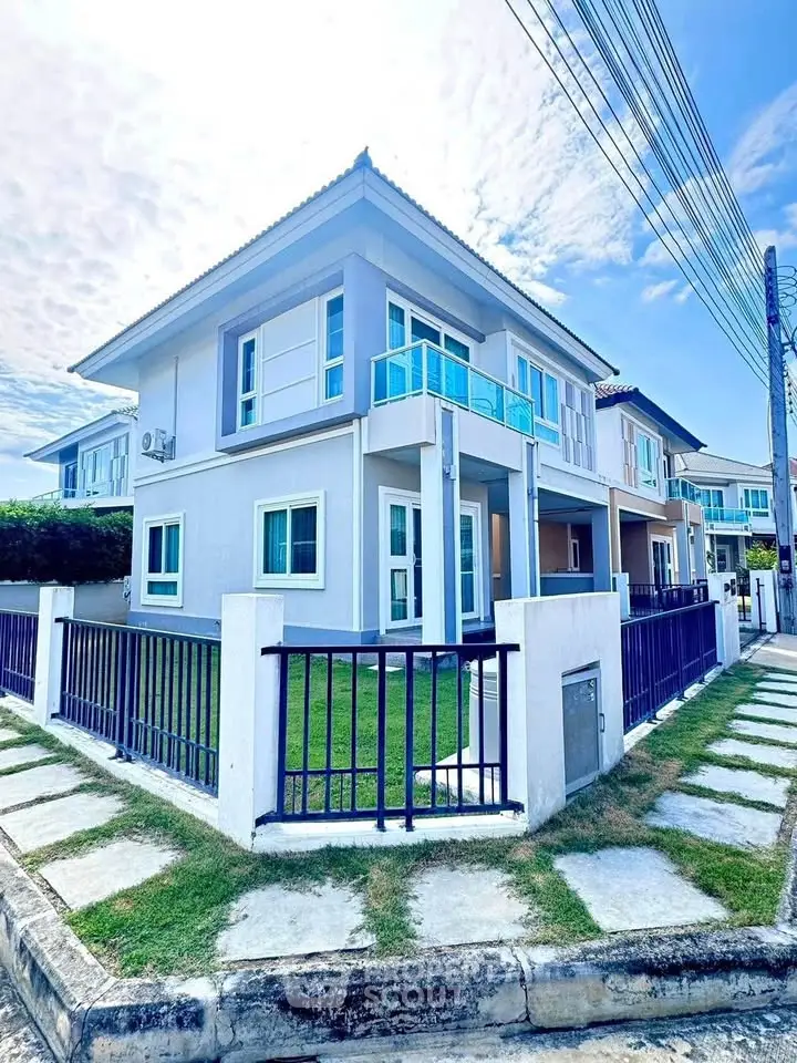 Modern two-story house with blue accents and fenced yard on a sunny day.