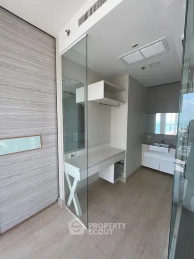 Modern bathroom with sleek design and glass partitions, featuring a stylish vanity and ample storage space.