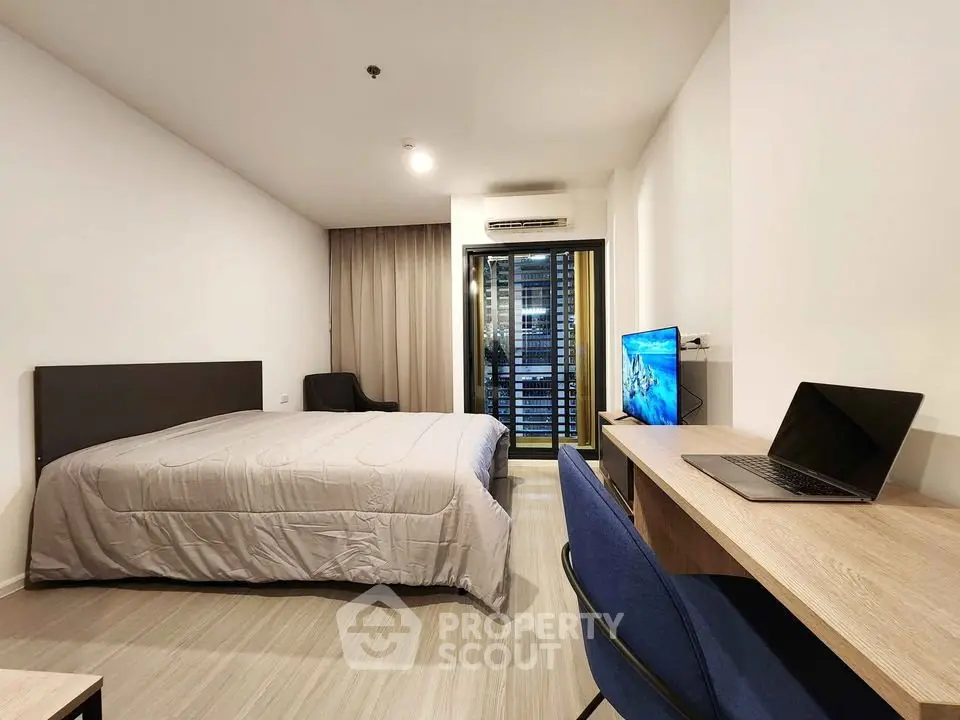 Modern bedroom with balcony view, featuring a sleek workspace and cozy ambiance.