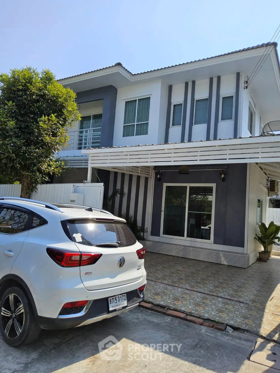 Modern two-story house with carport and stylish facade in a suburban neighborhood.