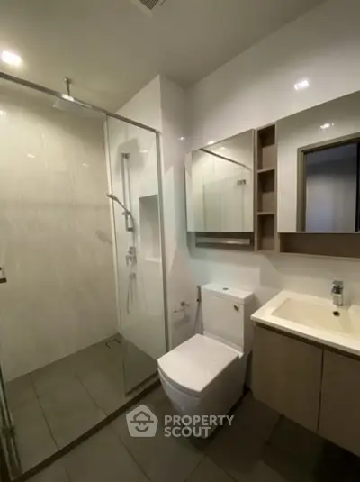 Modern bathroom with glass shower and sleek fixtures in a contemporary apartment.