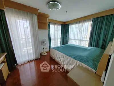 Spacious bedroom with large windows and elegant curtains in a modern apartment.