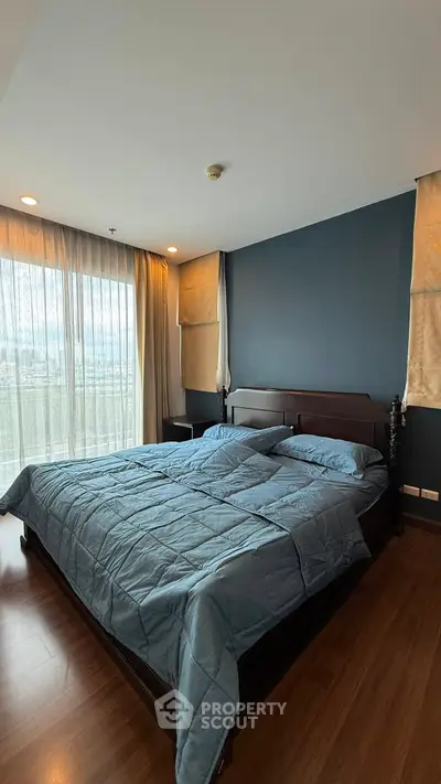 Spacious bedroom with large windows and modern decor, featuring a comfortable bed and elegant wooden flooring.