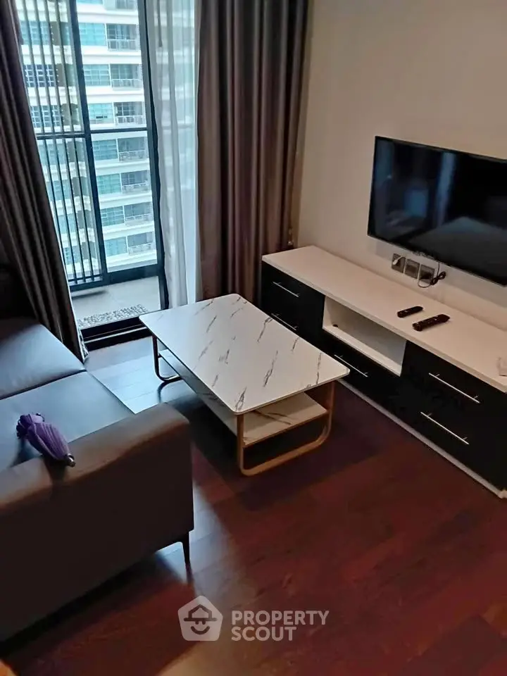 Modern living room with sleek furniture and large window view in urban apartment.