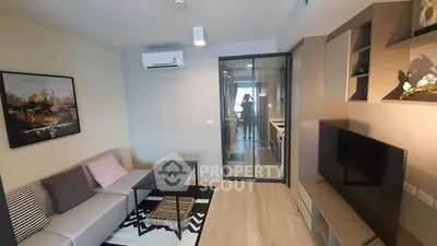 Modern living room with stylish decor and glass partition leading to kitchen.
