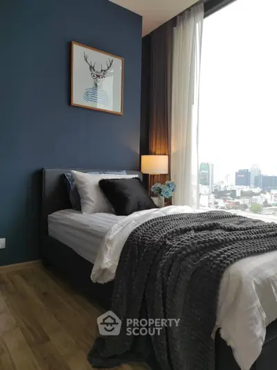 Cozy bedroom with city view, featuring stylish decor and natural light.