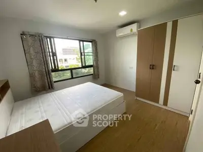Spacious bedroom with large window and modern wardrobe in a bright apartment.
