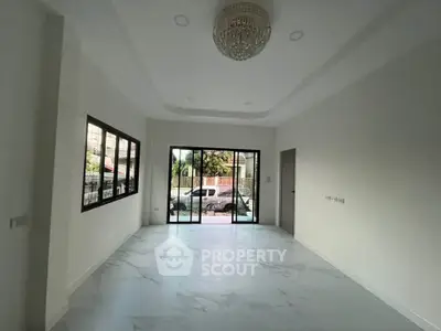 Spacious empty living room with large windows and elegant chandelier