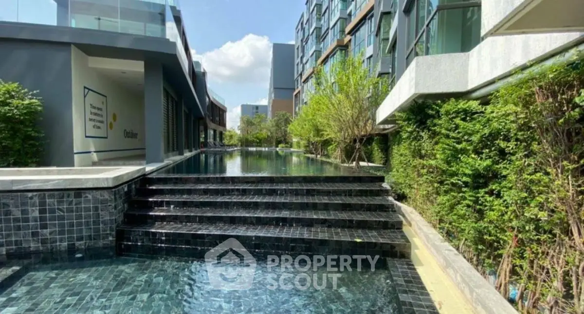 Luxurious modern apartment complex with stunning outdoor pool and lush greenery.