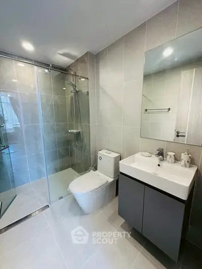 Modern bathroom with glass shower and sleek fixtures in contemporary apartment.
