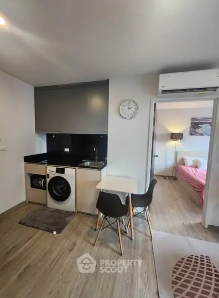 Modern compact kitchen with washing machine and dining area in cozy apartment