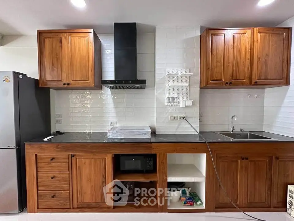 Modern kitchen with wooden cabinets, sleek black countertop, and stainless steel appliances