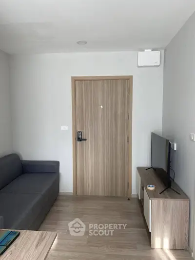 Modern living room with sleek furniture and wooden flooring, featuring a cozy sofa and flat-screen TV.