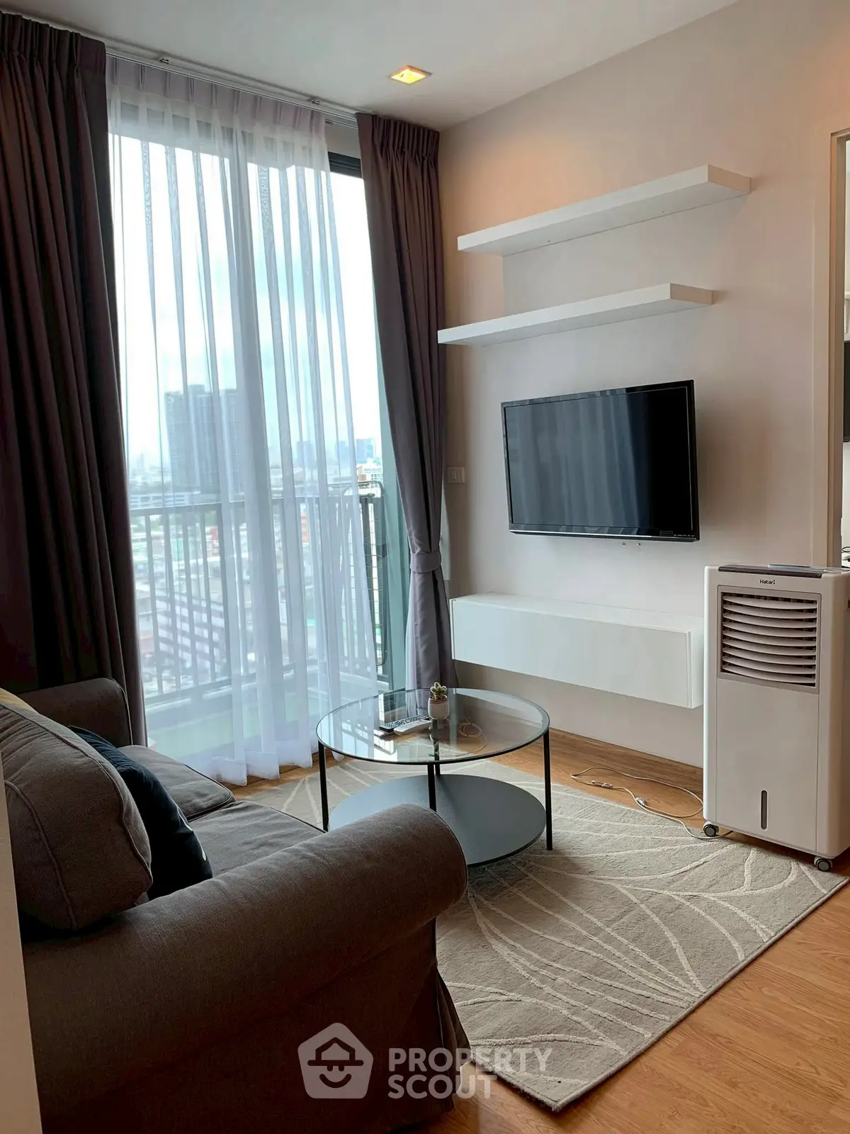 Modern living room with city view, cozy sofa, and sleek TV setup.