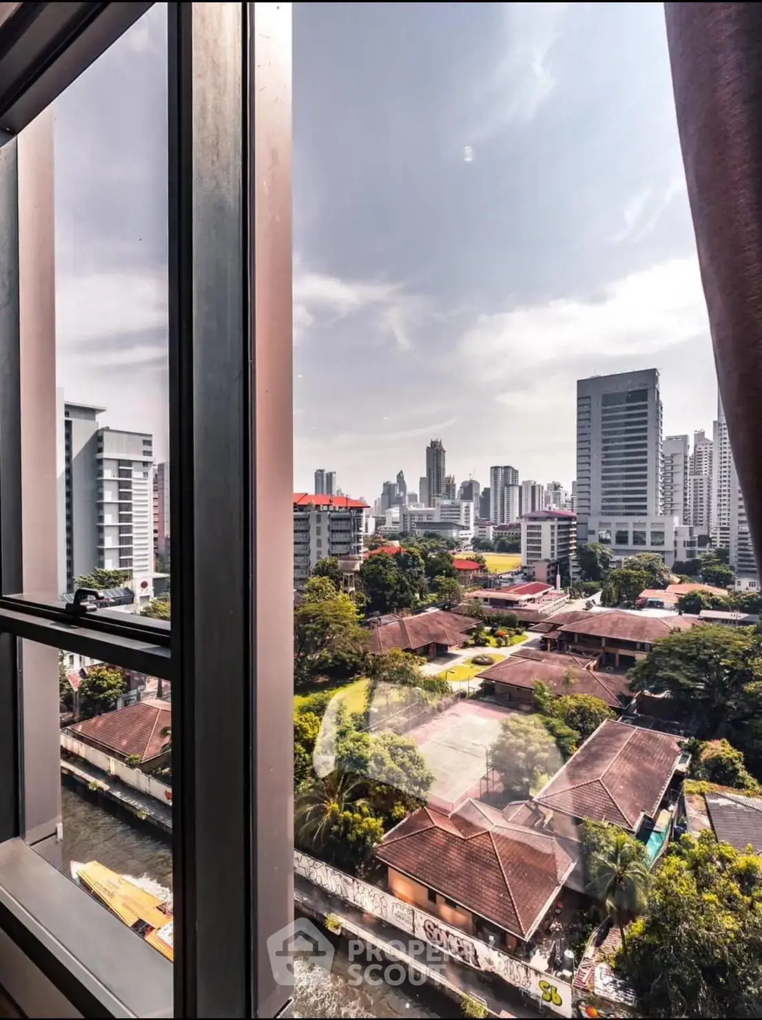 Stunning cityscape view from high-rise window showcasing urban skyline and lush greenery.