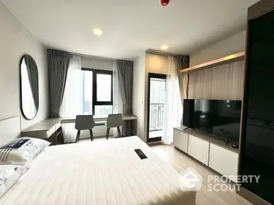 Modern bedroom with balcony and city view, featuring sleek furniture and large TV.