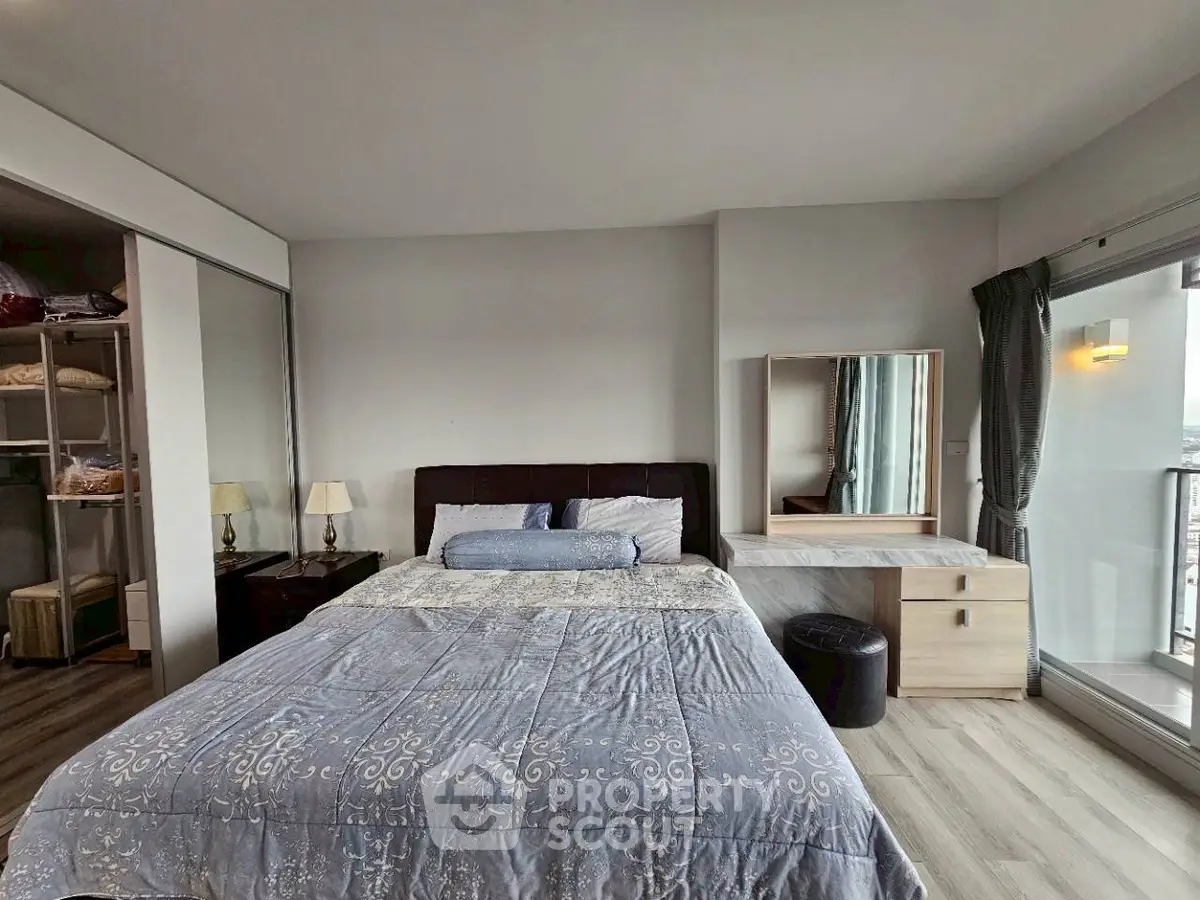 Spacious bedroom with modern decor and balcony access, featuring elegant furnishings and ample natural light.