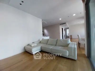Spacious living room with modern white sofa and wooden flooring in open layout apartment.