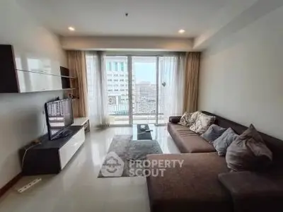Spacious living room with modern sofa and city view balcony in high-rise apartment.