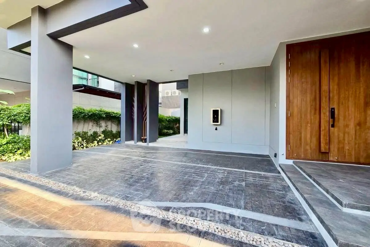 Modern building entrance with sleek design and lush greenery, showcasing contemporary architecture and inviting ambiance.