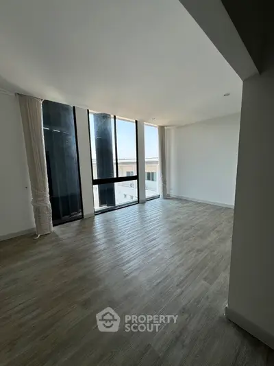Spacious modern living room with large windows and wooden flooring