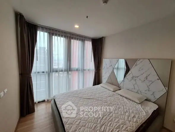 Modern bedroom with large windows and stylish decor in a high-rise apartment.