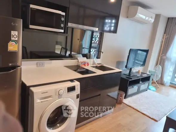 Modern kitchen with washing machine and sleek appliances in cozy living area.