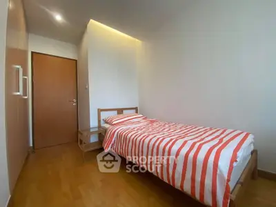 Cozy bedroom with single bed and wooden flooring in modern apartment.