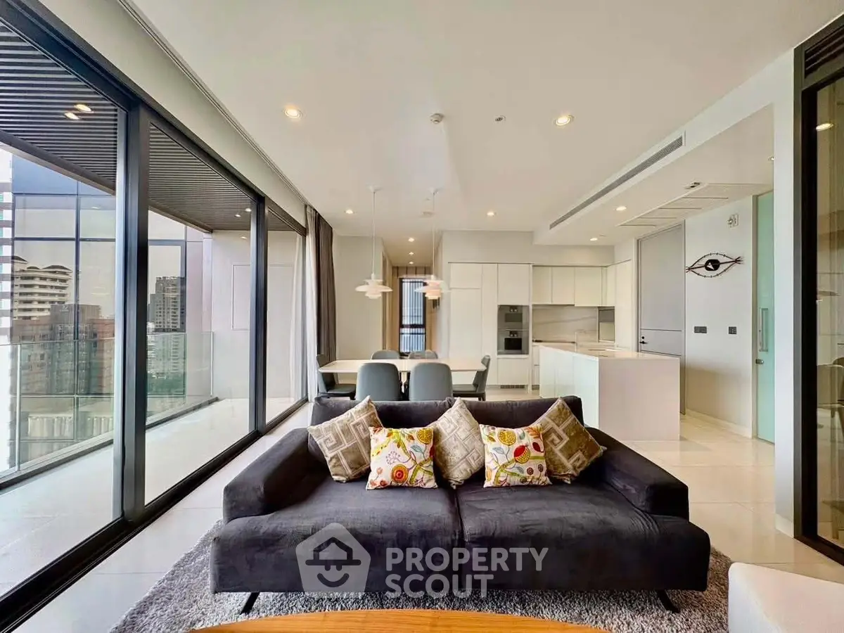 Luxurious modern living room with floor-to-ceiling windows and open kitchen layout in high-rise apartment.