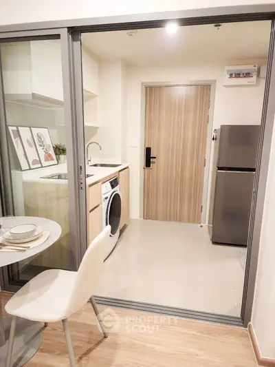 Modern compact kitchen with washing machine and fridge, perfect for urban living.