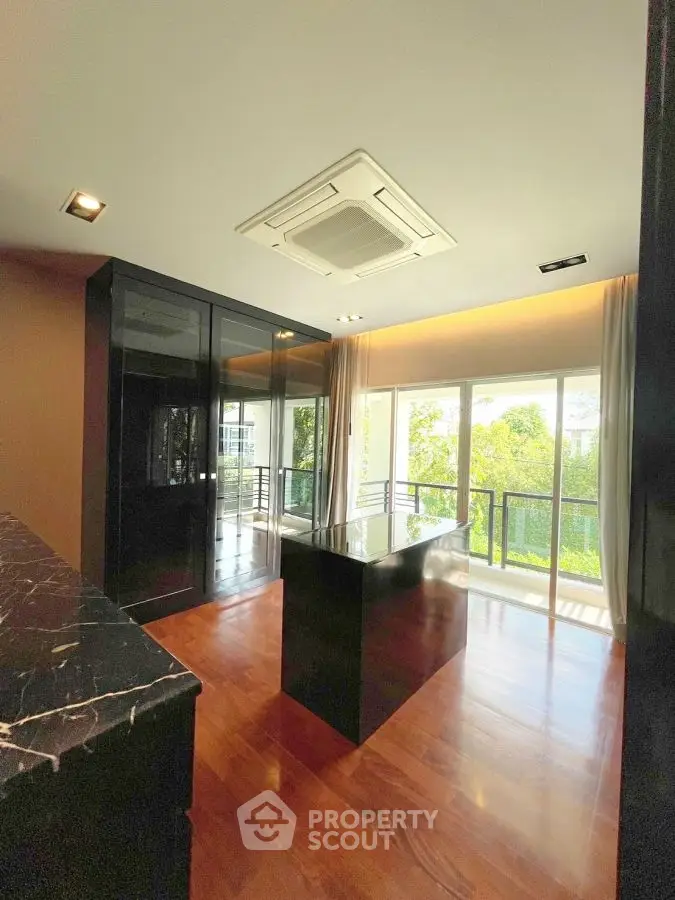 Luxurious modern kitchen with sleek black cabinetry and island, overlooking a lush green view.