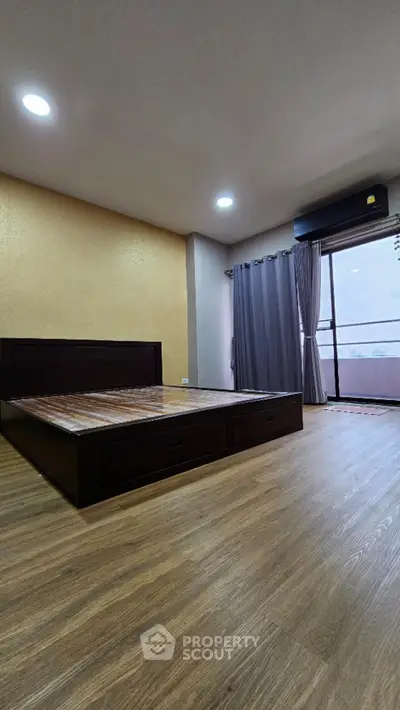 Spacious bedroom with wooden flooring and balcony access