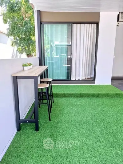 Modern balcony with artificial grass and stylish bar table set, perfect for relaxation.