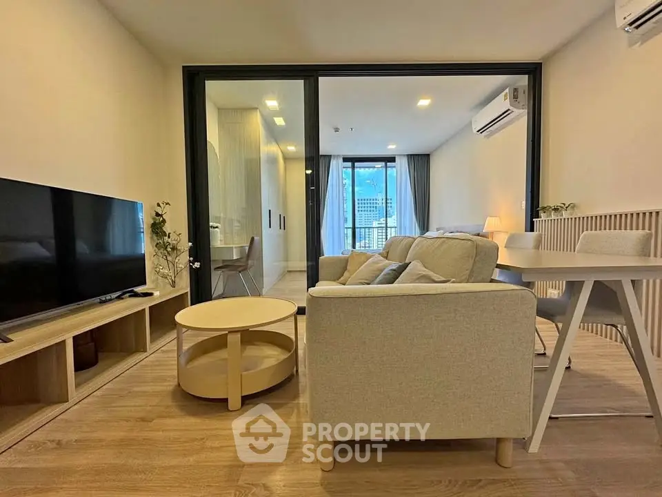 Modern living room with stylish furniture and large TV, featuring a view of the city skyline.