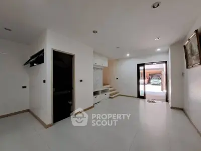 Spacious modern living room with sleek white tiles and large windows for natural light.