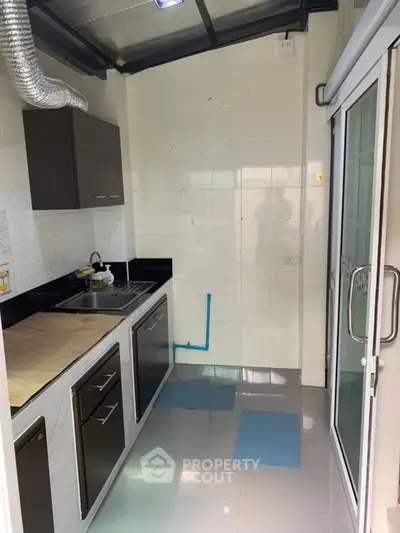 Modern kitchen with sleek cabinets and stainless steel sink in compact layout.