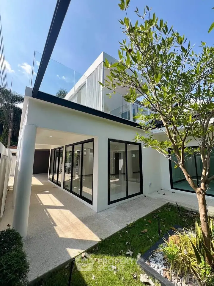 Modern two-story house with large windows and lush garden
