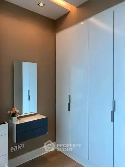Modern bedroom with sleek wardrobe and stylish mirror in a contemporary apartment.