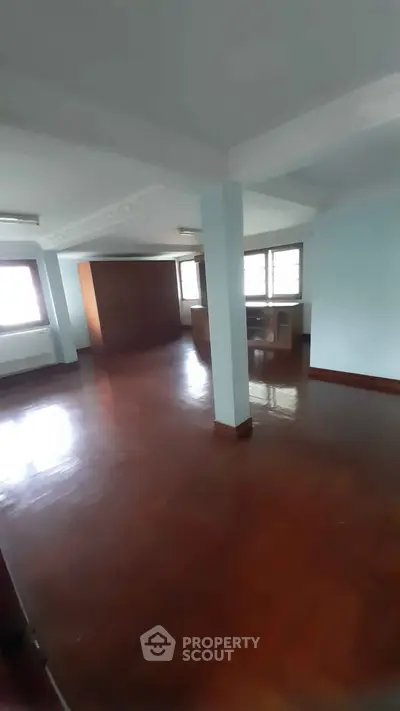 Spacious living room with polished wooden floors and large windows for natural light.