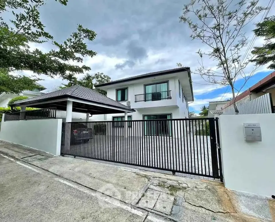 Modern two-story house with gated driveway and lush greenery