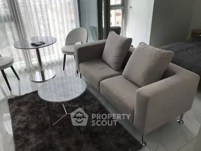 Modern living room with cozy sofa, marble tables, and plush rug in a bright apartment.