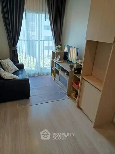 Cozy living room with modern decor and large window view in urban apartment.