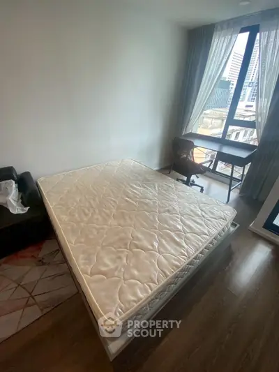 Spacious bedroom with large window and city view, featuring a comfortable bed and a work desk.