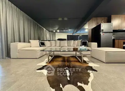 Luxurious modern living room with stylish decor and open kitchen layout, featuring a chic cowhide rug and sleek furniture.