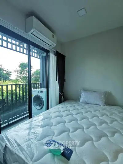 Cozy bedroom with balcony view and washing machine, perfect for modern living.