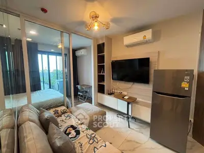 Modern living room with sleek furniture and large TV, adjacent to a cozy bedroom.