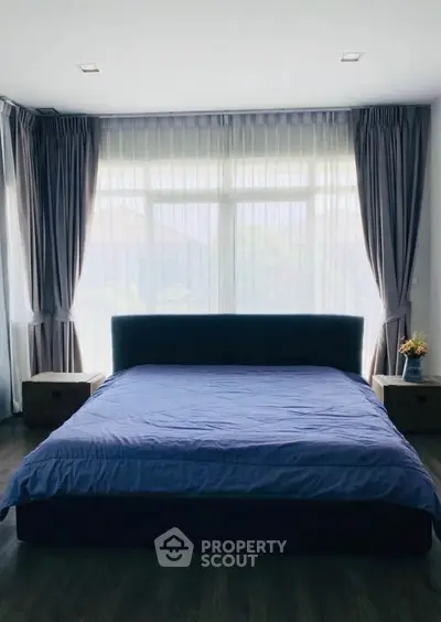 Spacious bedroom with large windows and elegant curtains, perfect for natural light lovers.
