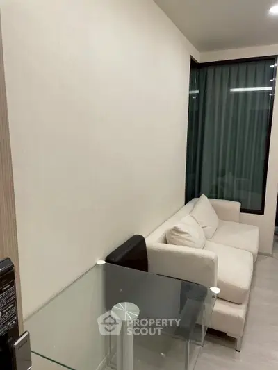 Modern living room with cozy white sofa and glass table, perfect for relaxation and entertainment.