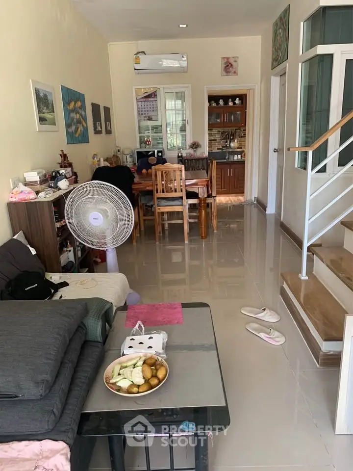 Cozy living room with dining area and staircase, featuring modern decor and natural light.